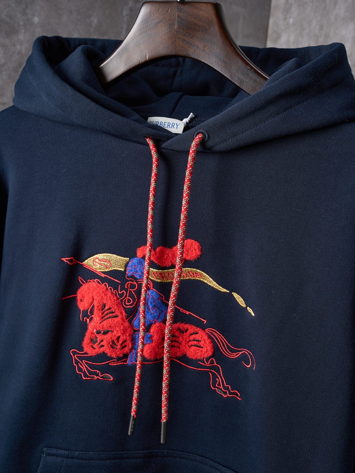 Navy hoodie hood with red drawstrings and colorful embroidered emblem