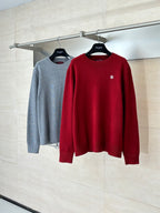 Red and gray Gucci crewneck sweaters on hangers with GG logo details