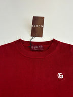 Red Gucci crewneck sweater close-up with GG logo on the chest