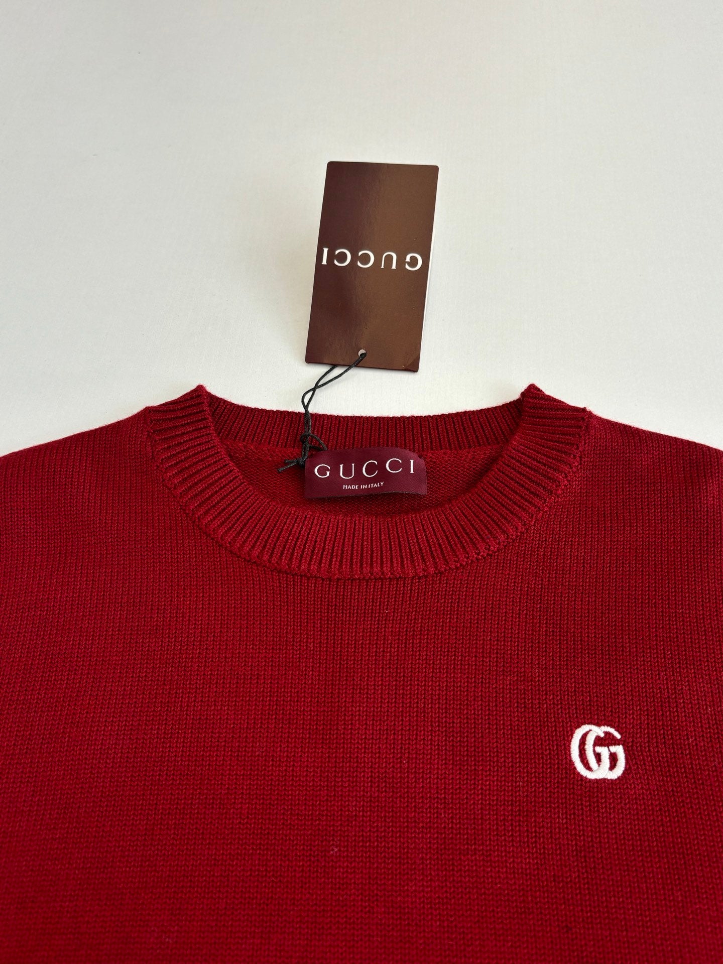 Red Gucci crewneck sweater close-up with GG logo on the chest