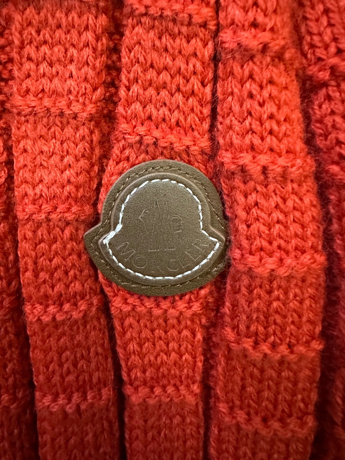 Red knit sweater sleeve with stitched leather-look patch detail