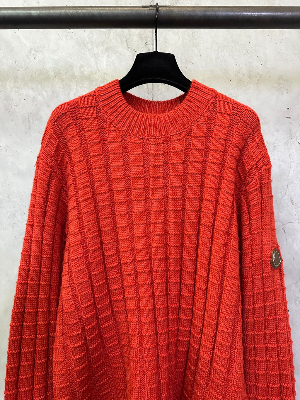 Red crew-neck knit sweater with repeating check pattern and long sleeves