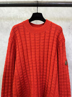 Red crew-neck knit sweater with repeating check pattern and long sleeves