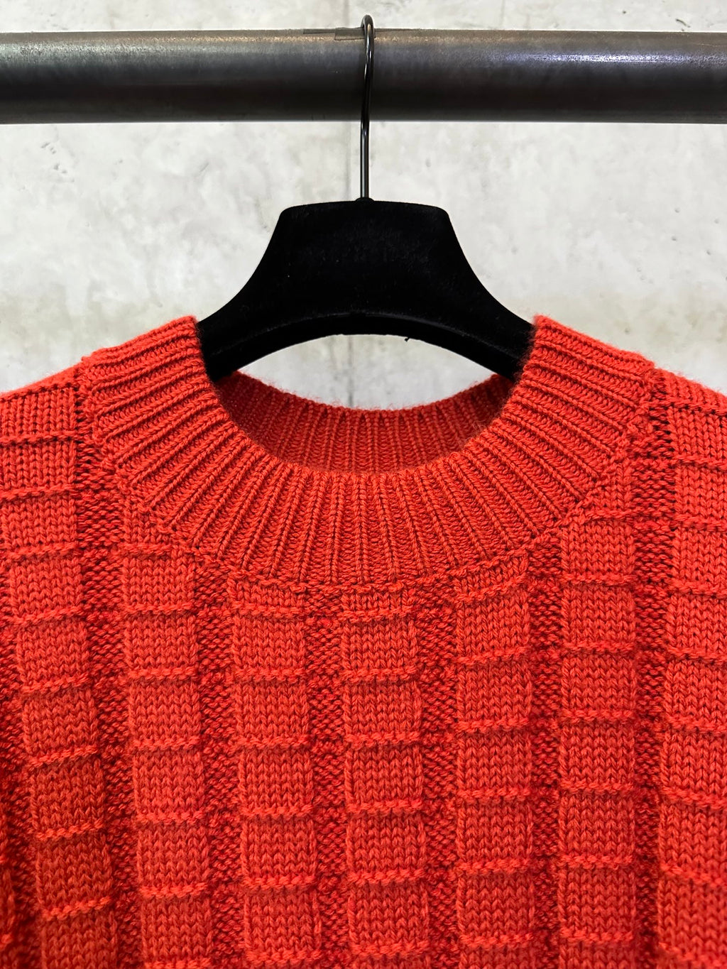 Red crew-neck knit sweater collar detail with ribbed edge and grid stitch