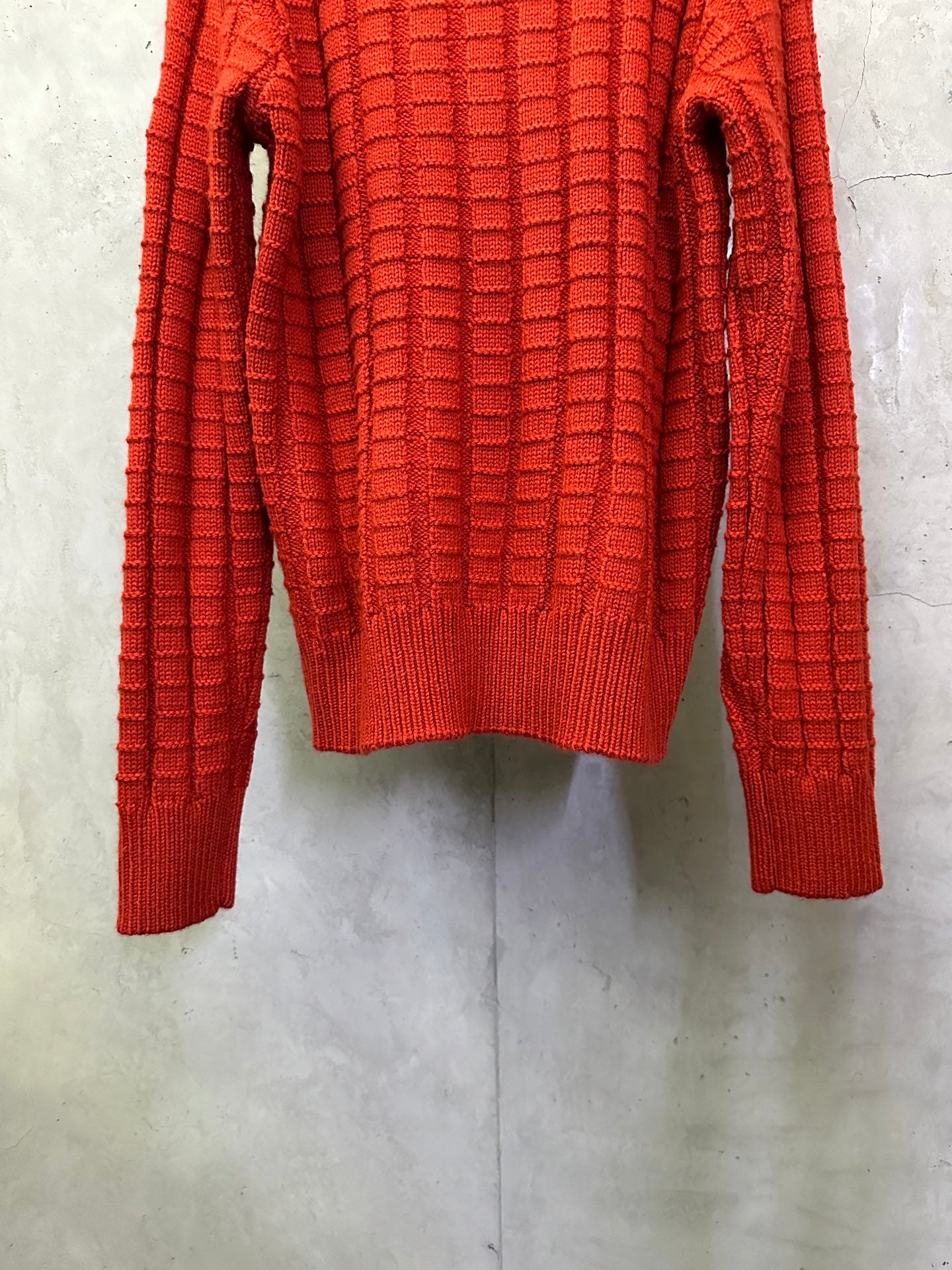 Red long-sleeve knit sweater back view with ribbed cuffs and hem