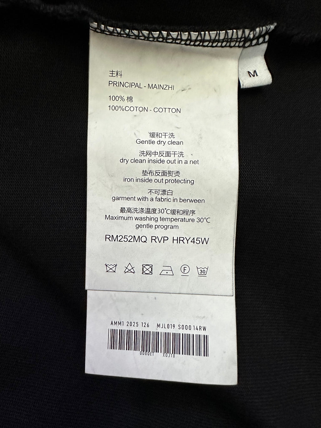 Black T-shirt care label with size M and fabric/care instructions