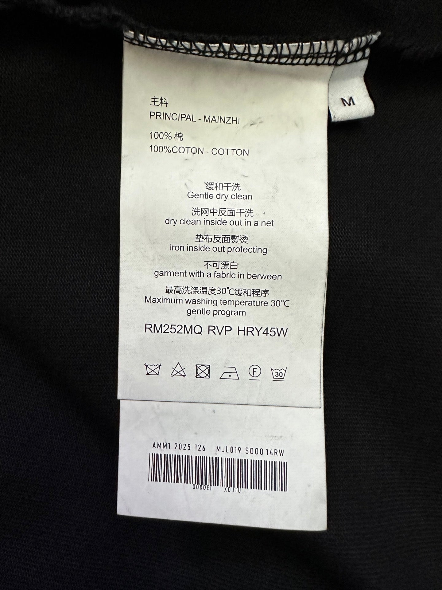 Black T-shirt care label with size M and fabric/care instructions