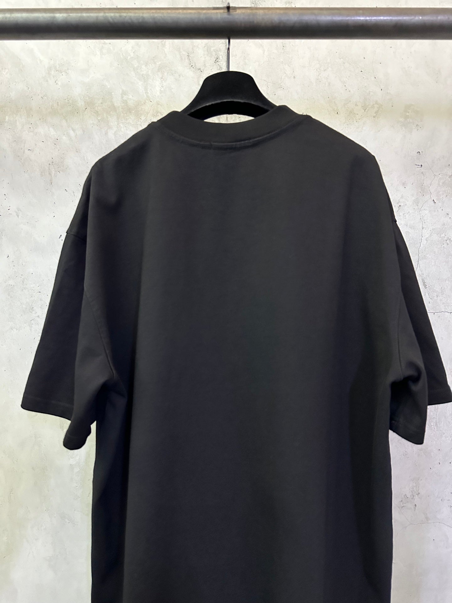 Black T-shirt back view on hanger, short sleeves and crew neckline