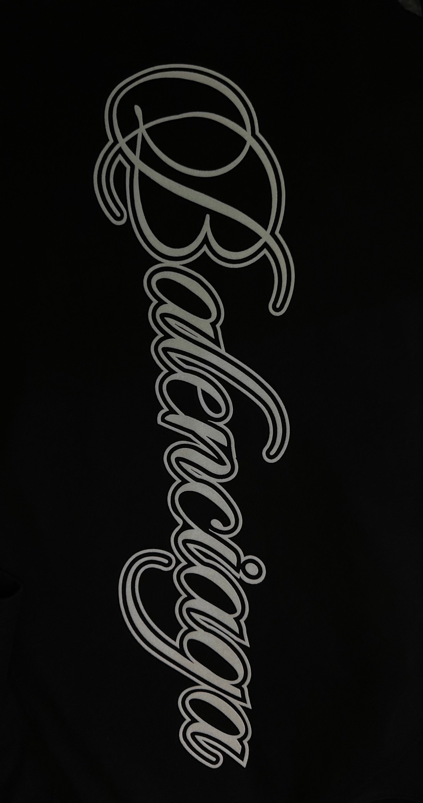 White script logo on black T-shirt fabric, close-up
