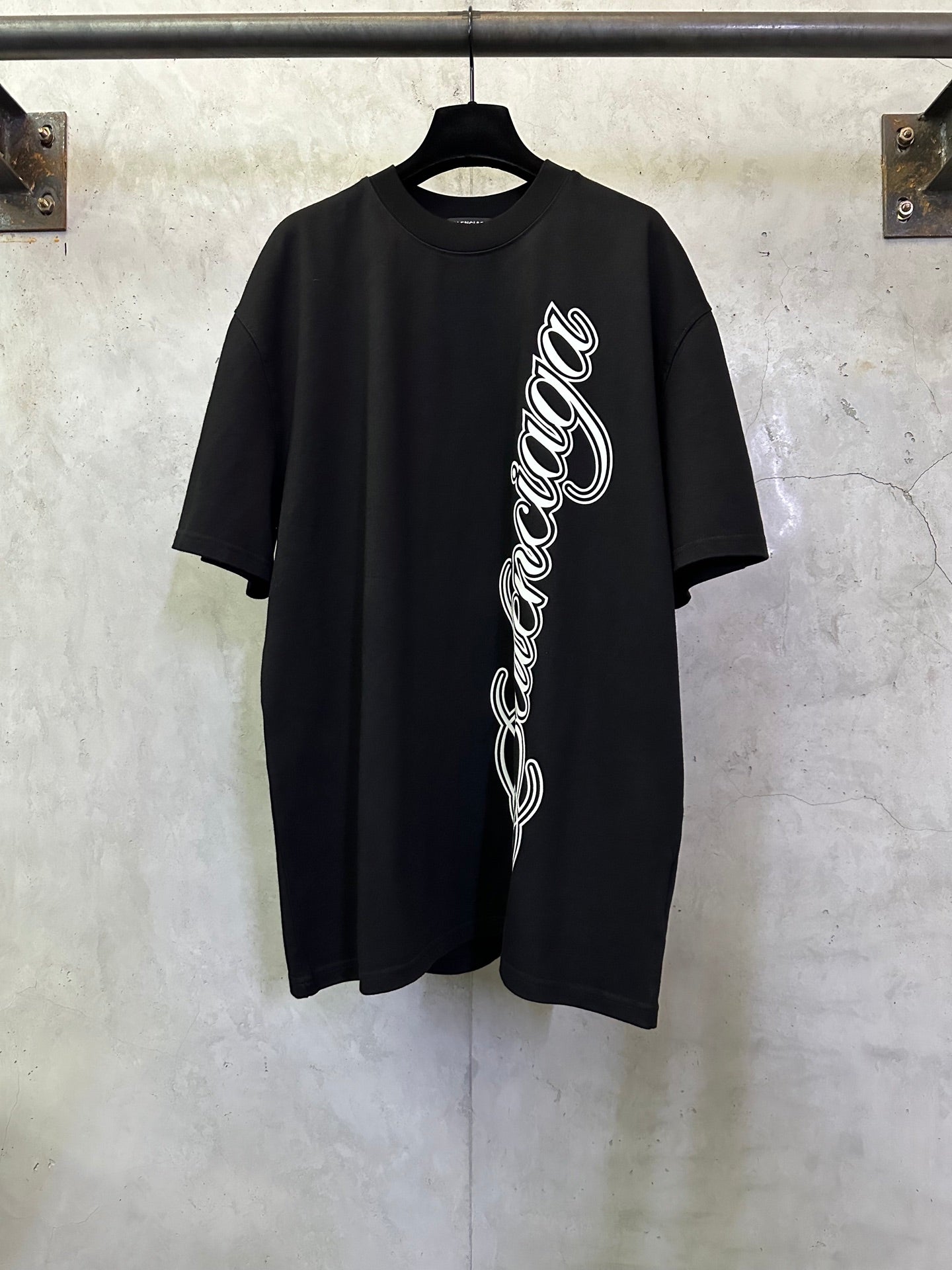 Black T-shirt with white script logo on the front, short sleeves, crew neck