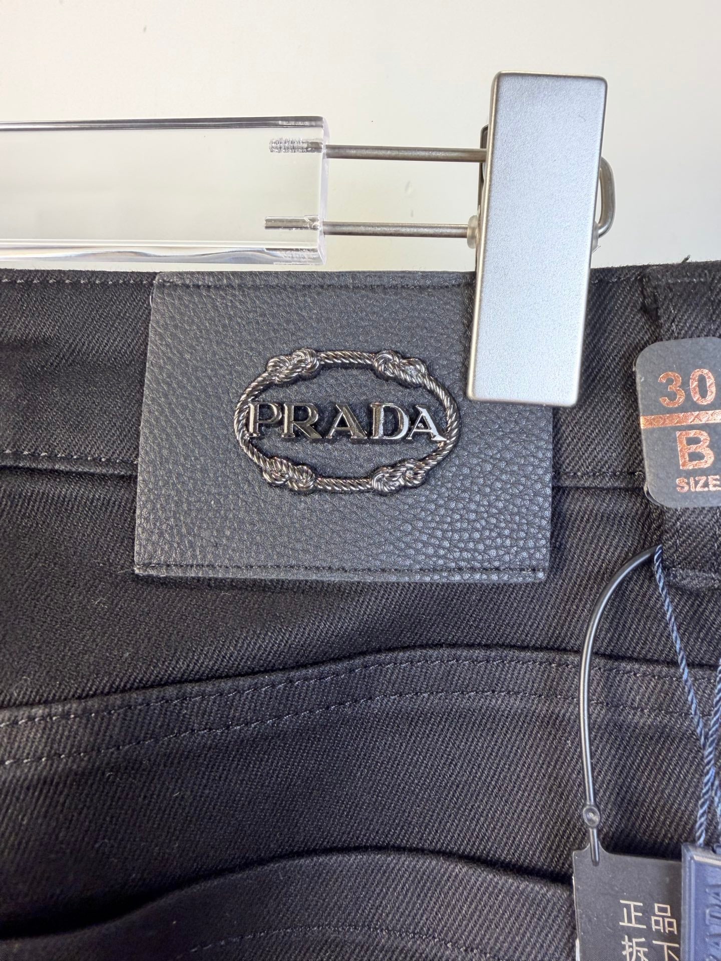Prada waist label and size tag attached to dark pants