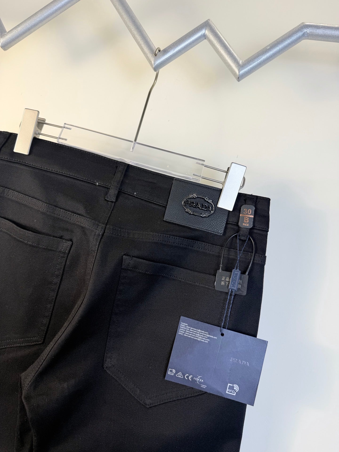 Prada pants waistband with stitched pockets and hanging product tags, dark blue