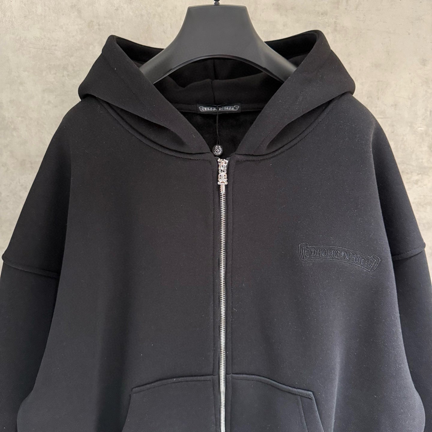 Dark zip-up hoodie close-up with hood and zipper at center front