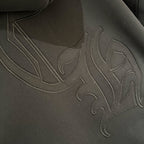 Dark hoodie front close-up with raised embroidered graphic across chest