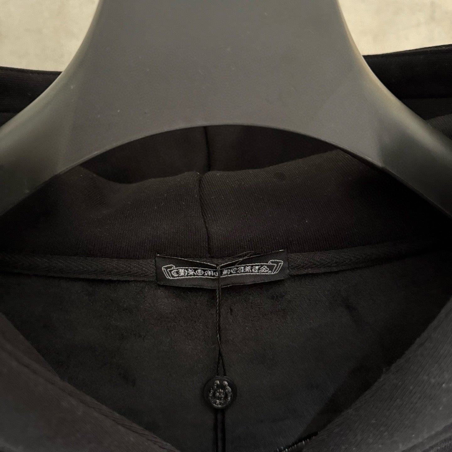 Dark hoodie inner neckline with sewn label and small black zipper pull