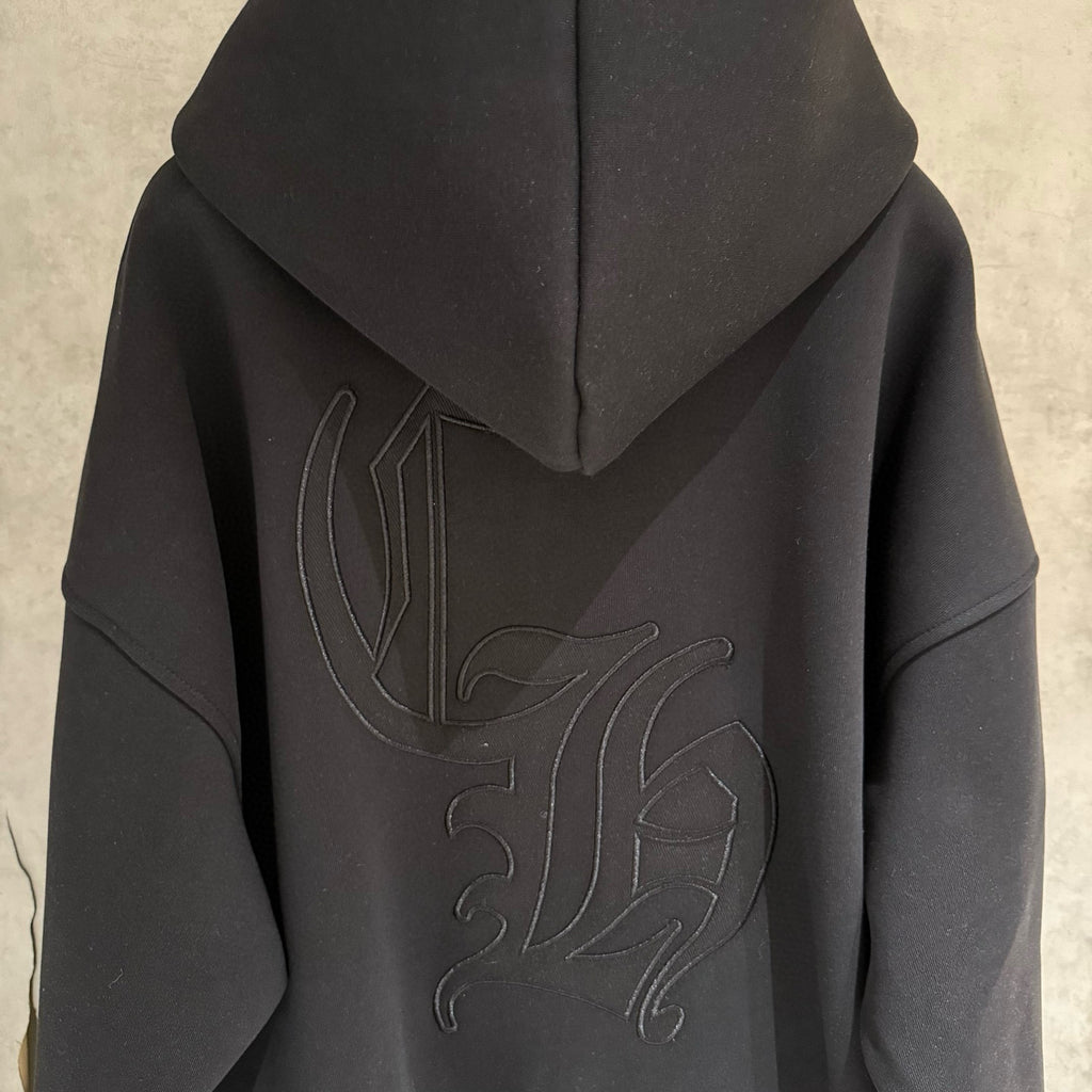 Dark hoodie back close-up with hood and raised embroidered graphic