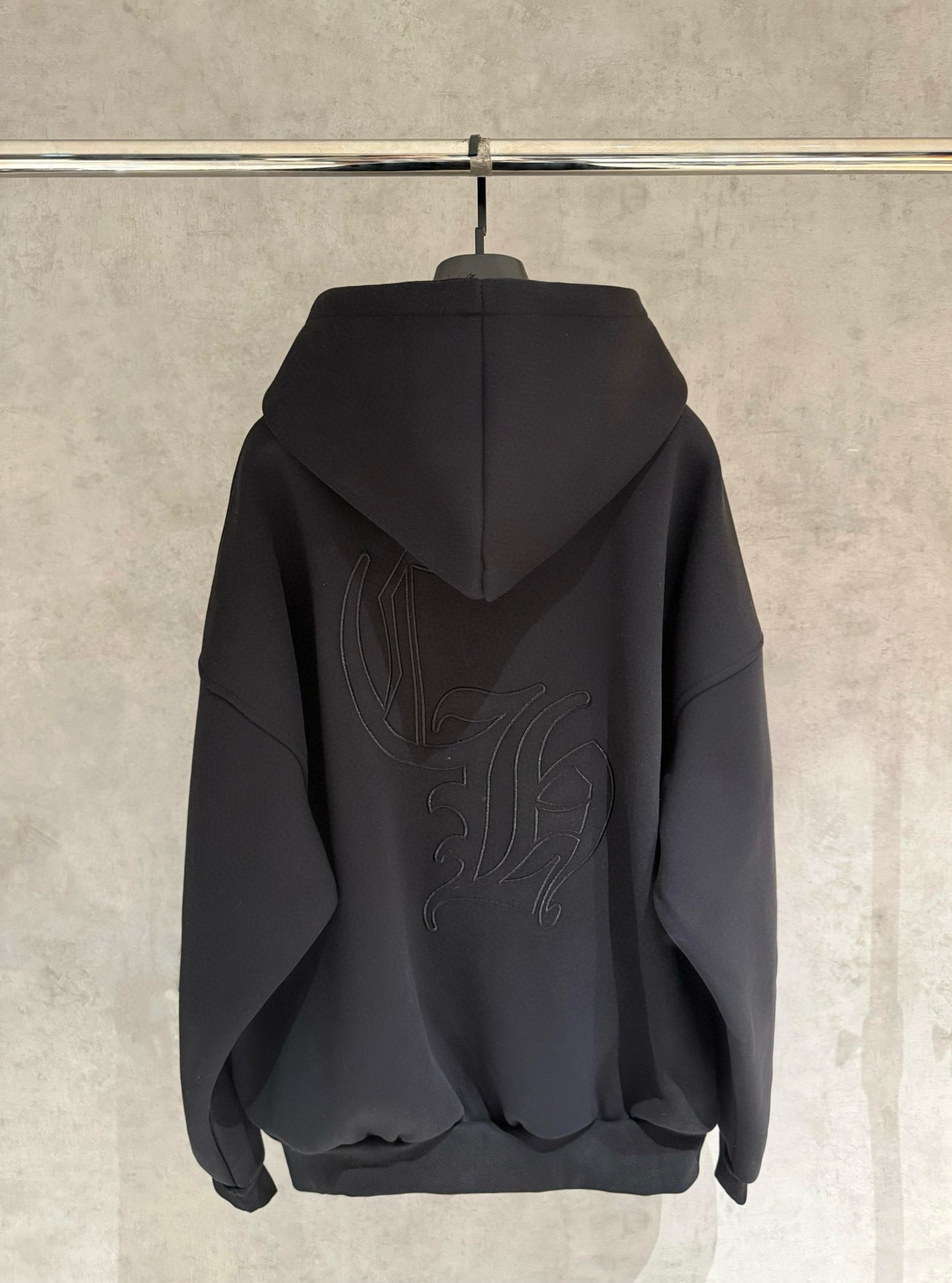Dark back view zip-up hoodie with hood and large embroidered graphic, hanging