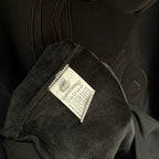Dark hoodie cuff close-up showing fabric care label sewn inside