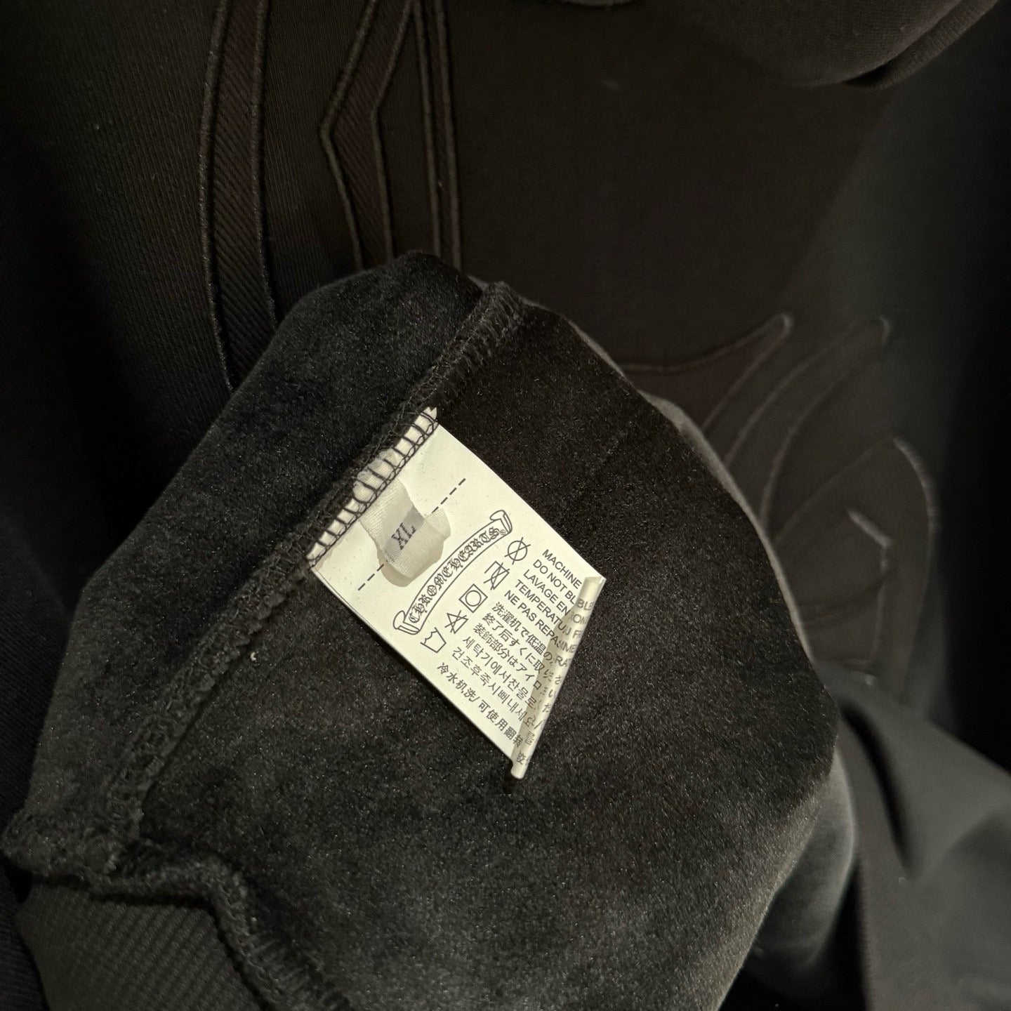 Dark hoodie cuff close-up showing fabric care label sewn inside