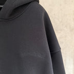 Dark hoodie sleeve close-up with small embossed logo detail