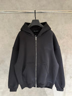 Dark zip-up hoodie with hood and front kangaroo pocket, hanging on a hanger