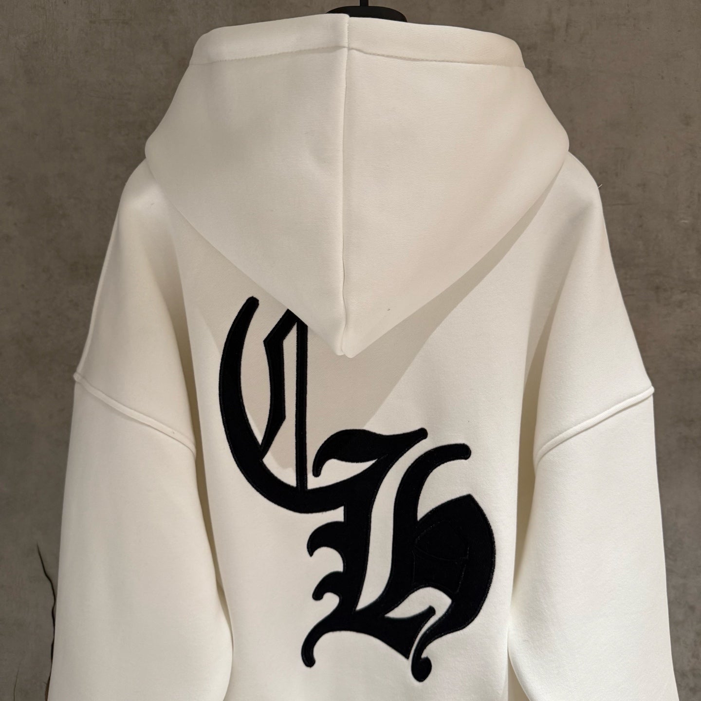 White hoodie back with large black emblem and hood
