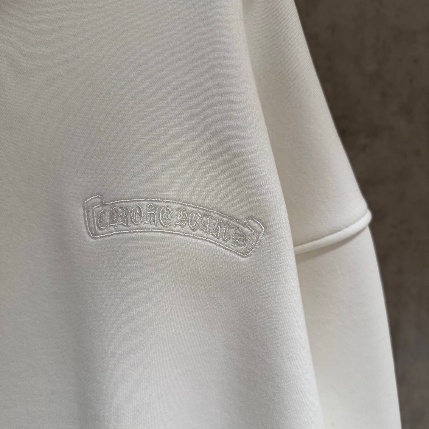 White hoodie with embossed logo on upper sleeve