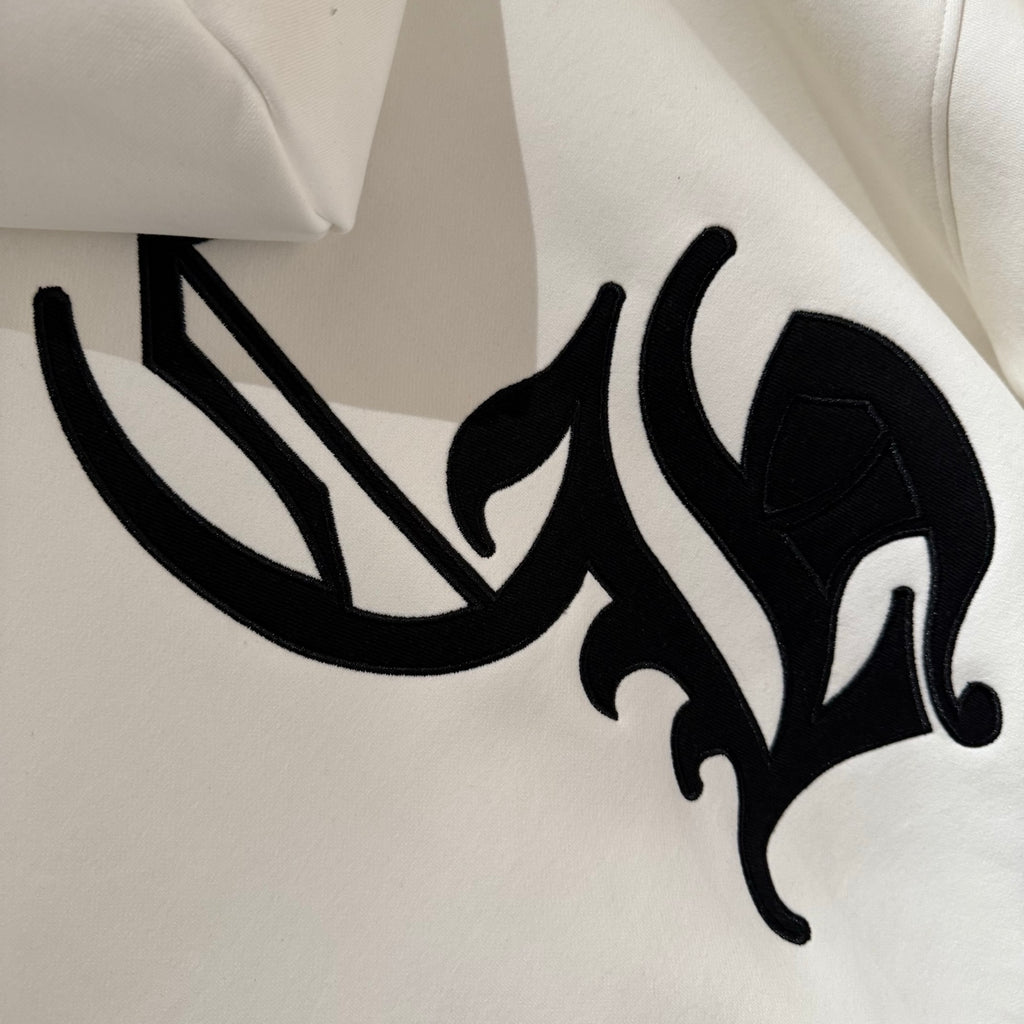 White hoodie with black ornate logo print on chest