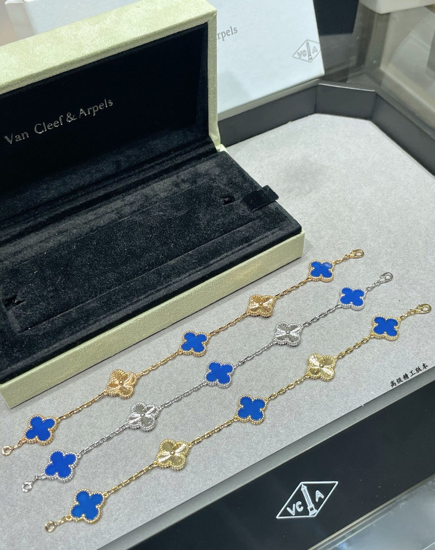Van Cleef & Arpels clover bracelet set with blue enamel and gold chain on black cushion