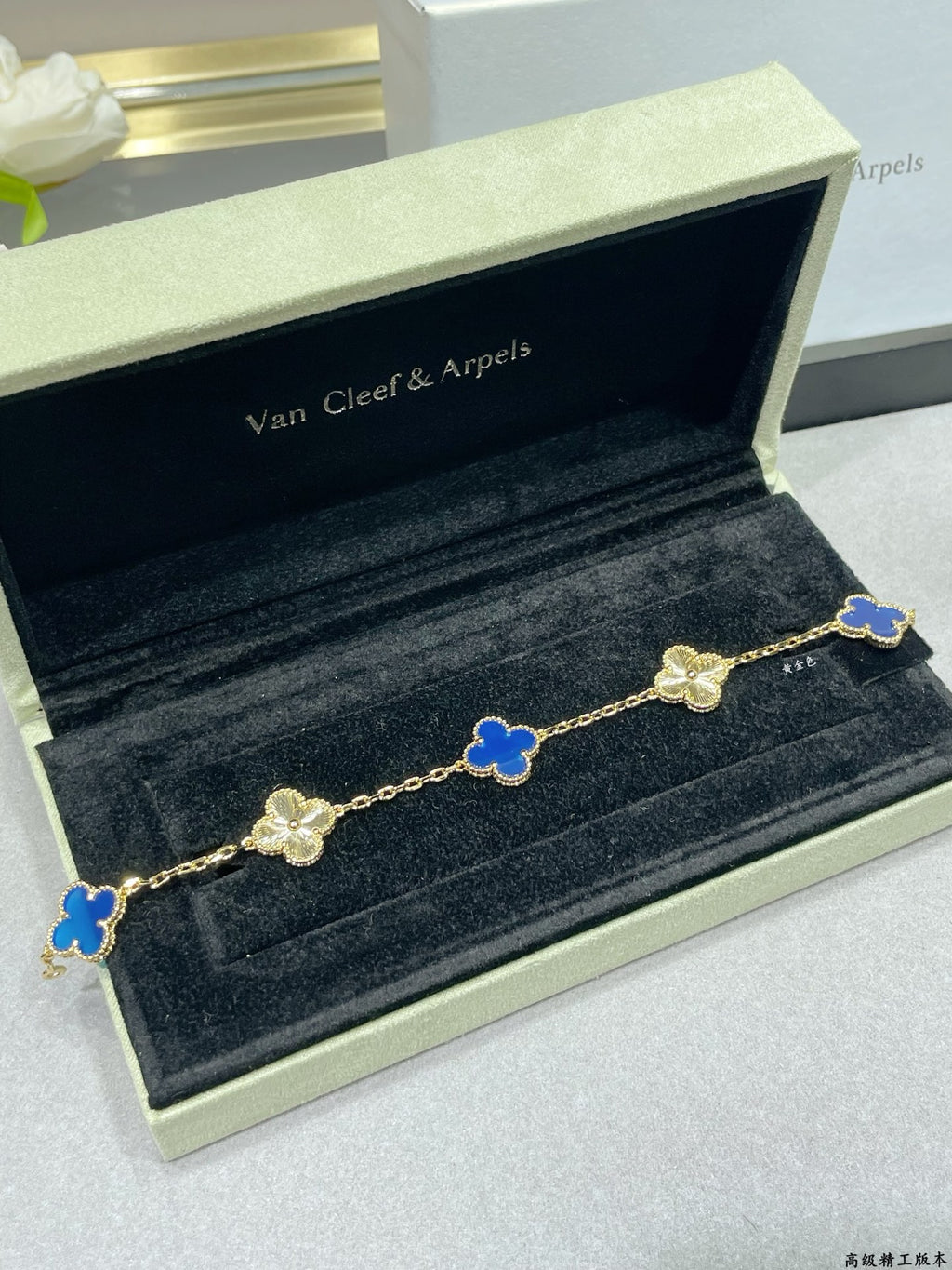 Van Cleef & Arpels clover bracelet with blue enamel motifs on gold chain on dark velvet tray