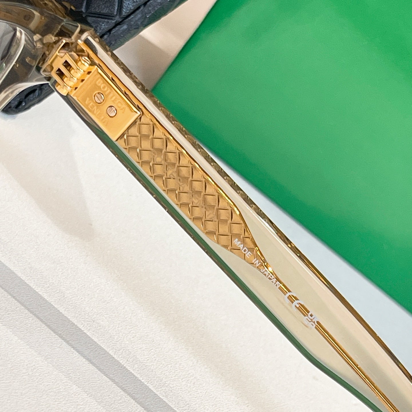 Gold-tone temple eyeglasses with embossed diamond texture and brand marks