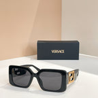 Black square sunglasses with gold Versace logo temples and gray lenses.