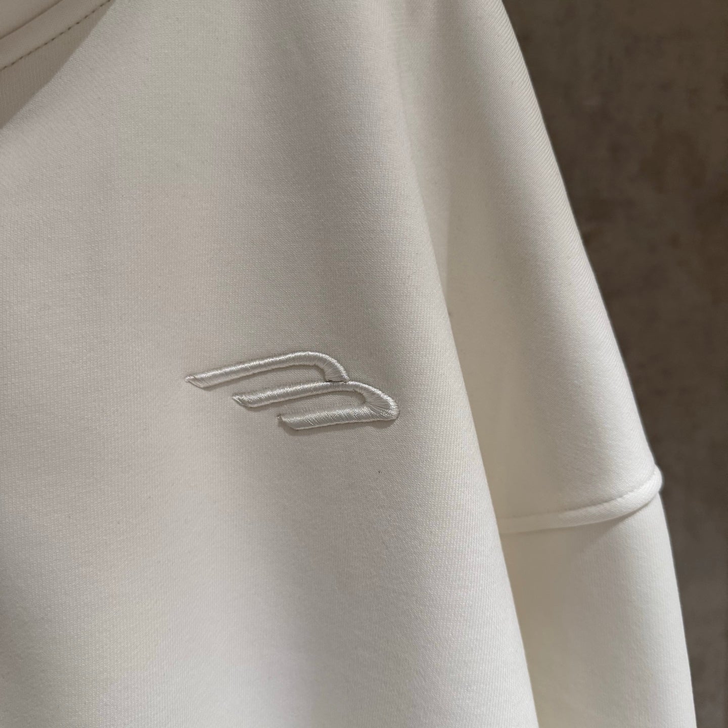 Balenciaga long hoodie sleeve with small embroidered logo on white fabric