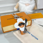 Louis Vuitton keychain charm on orange box: white flower, orange figure, silver clasp and ring
