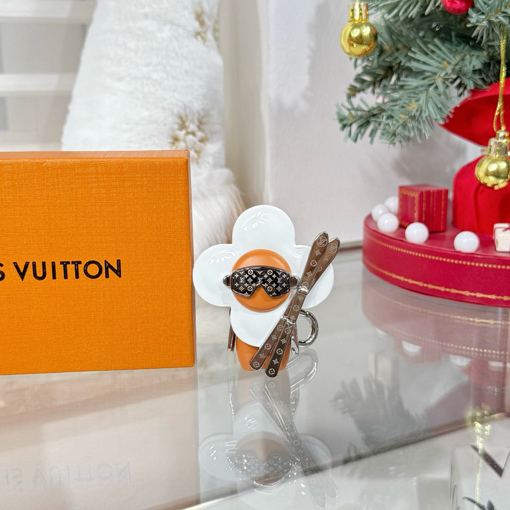 Louis Vuitton keychain charm featuring white flower wings and orange figure with silver hardware