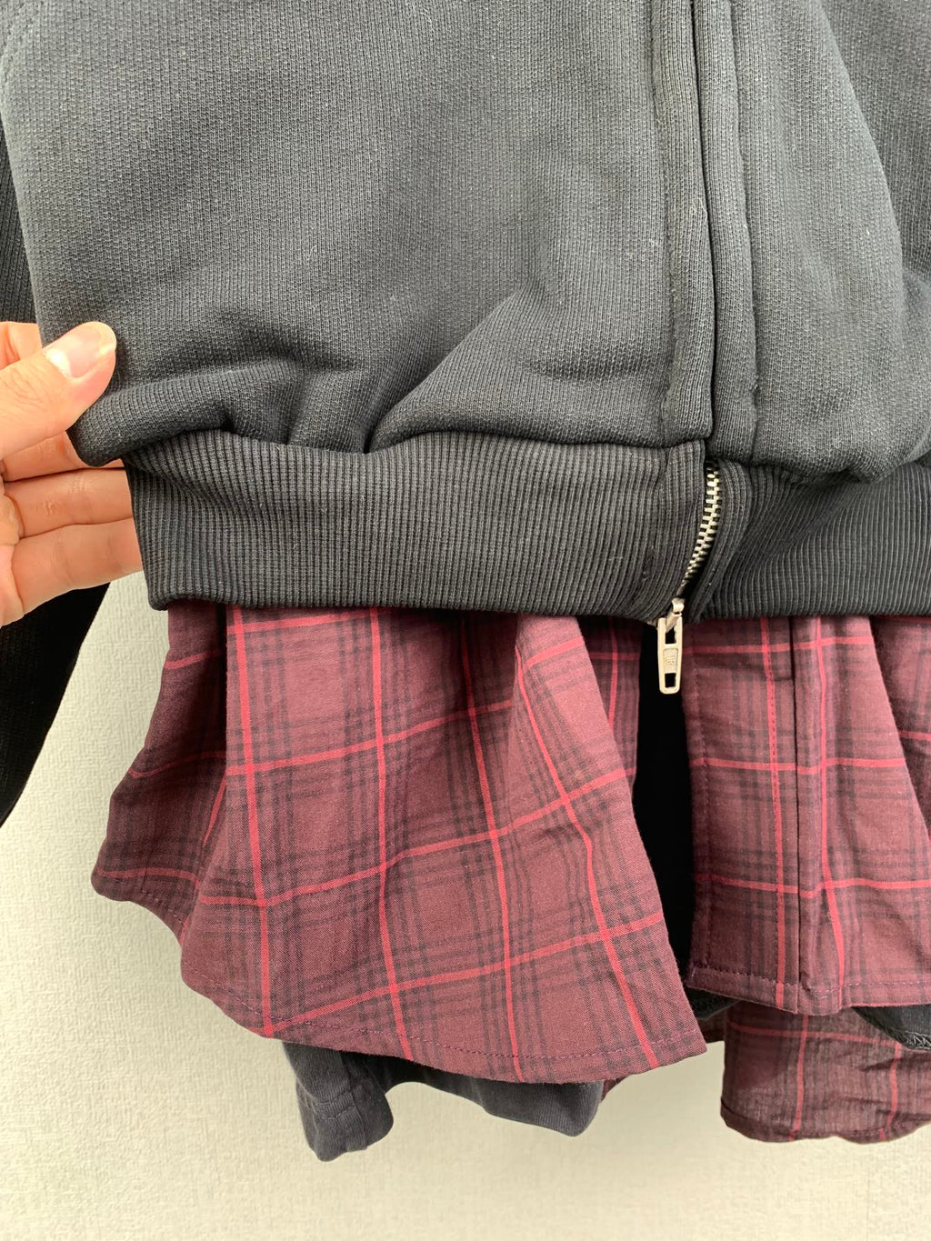 Zip-up hooded jacket cuff close-up with plaid inner shirt and contrast fabric layering
