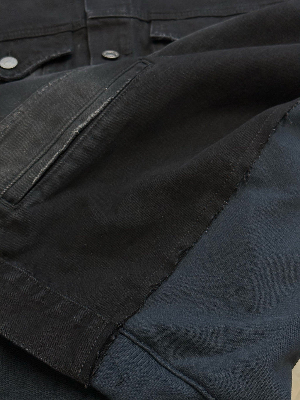Dark blue denim jacket sleeve and pocket seam with metal snap buttons