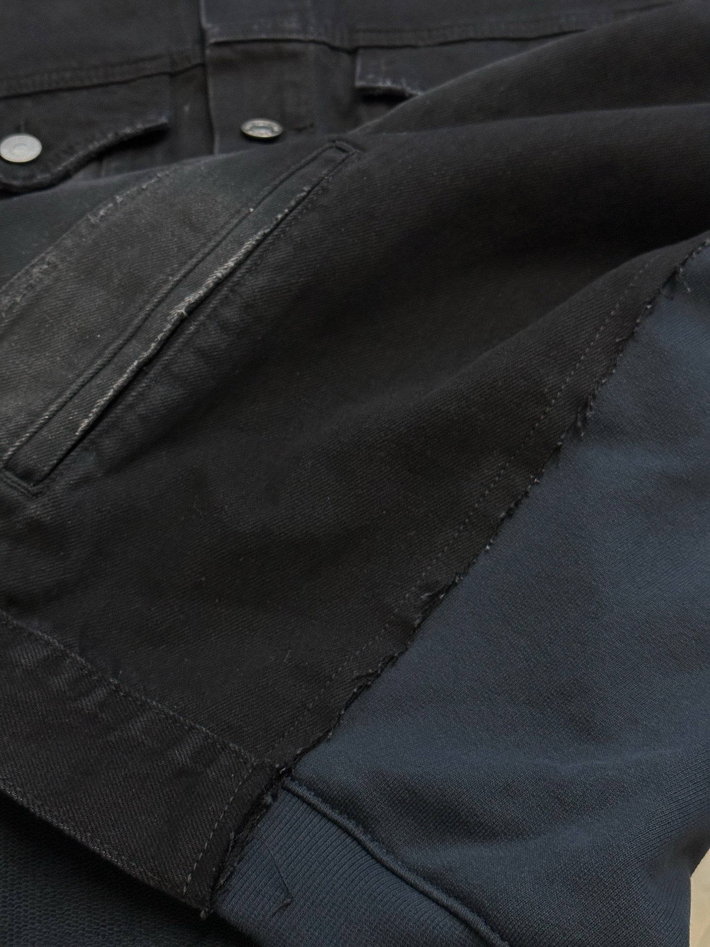 Dark blue denim jacket sleeve and pocket seam with metal snap buttons