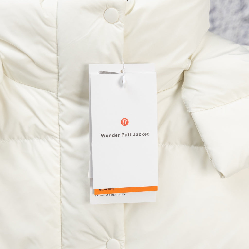 White puffer jacket close-up with snap button front and hanging product tag