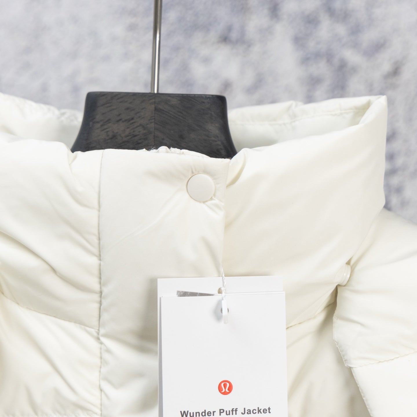 White puffer jacket with quilted panels and snap button front, close-up