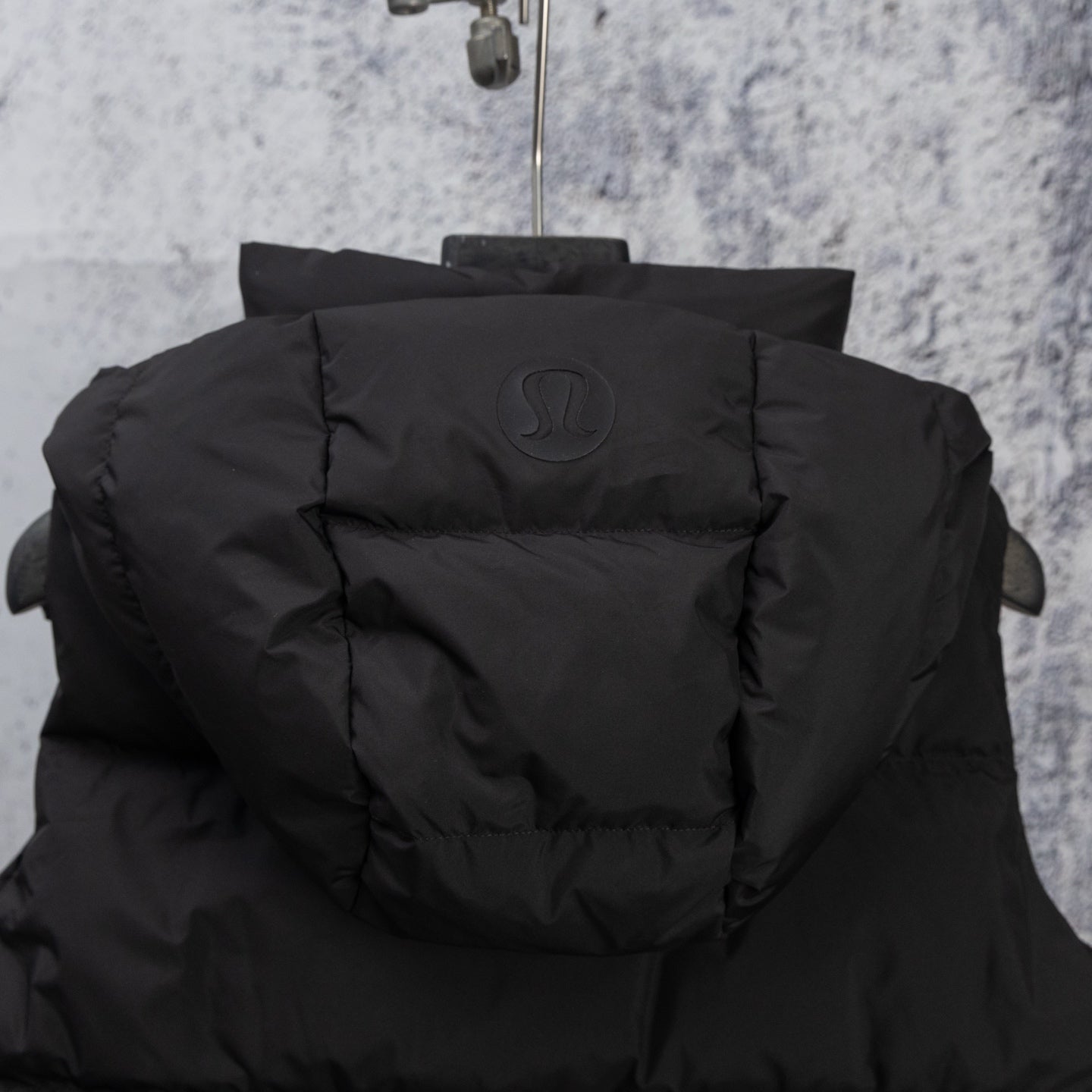 Black hooded puffer vest back view with embossed logo