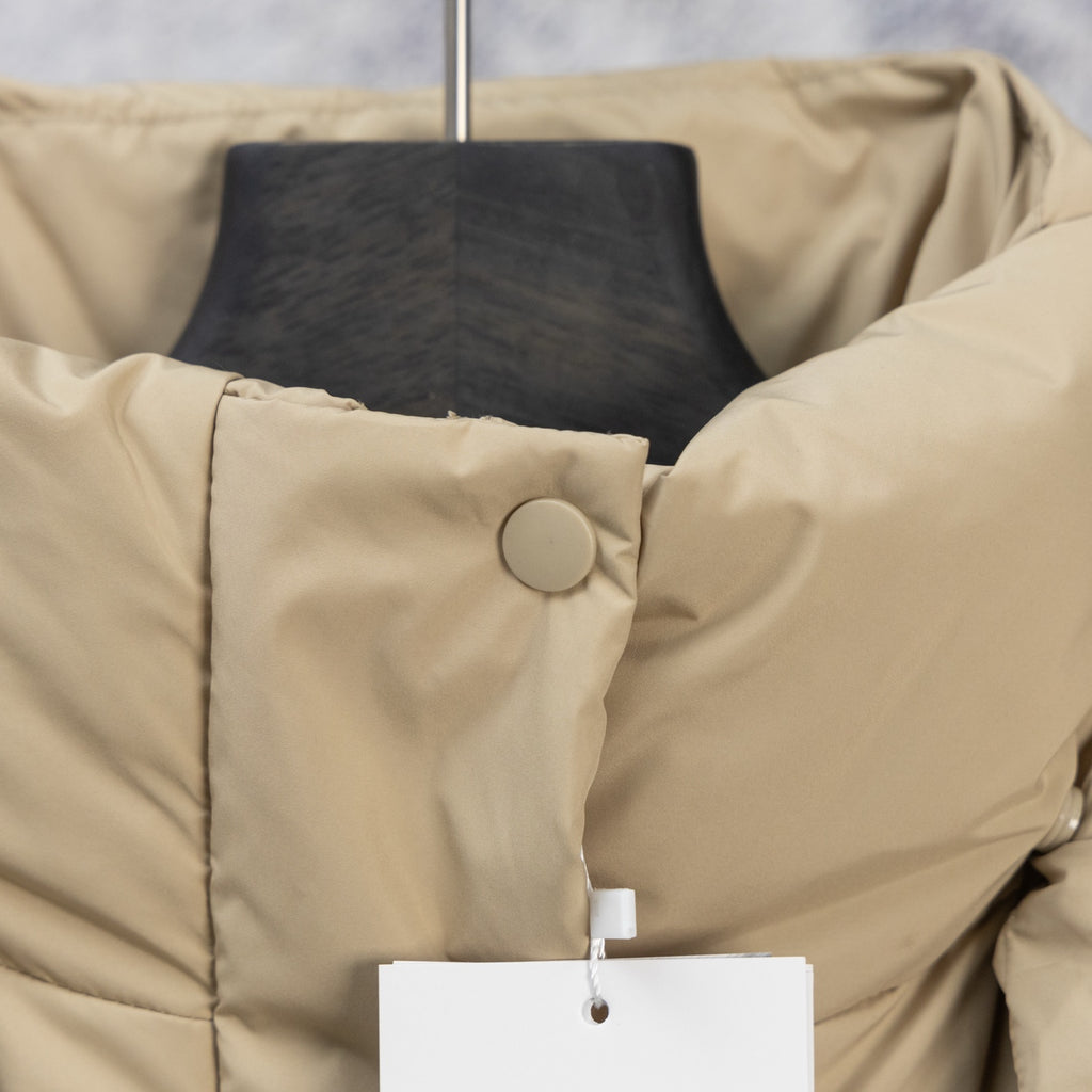 Beige puffer jacket close-up with snap button placket and quilted shoulders
