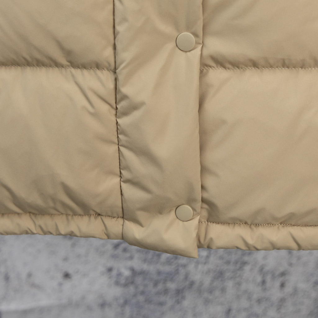 Beige puffer jacket front with two snap buttons and quilted lower panel