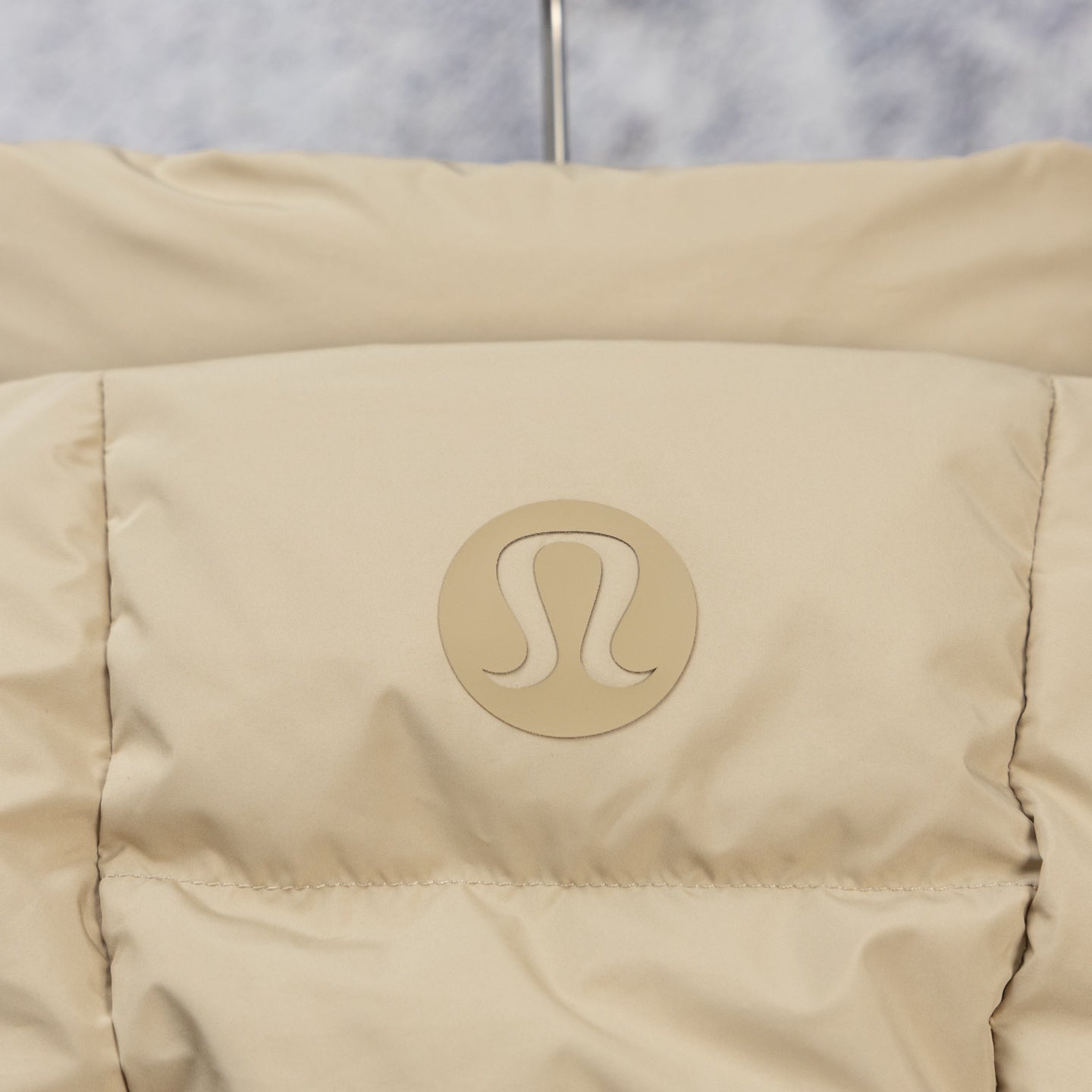 Tan puffer jacket back panel with embossed logo