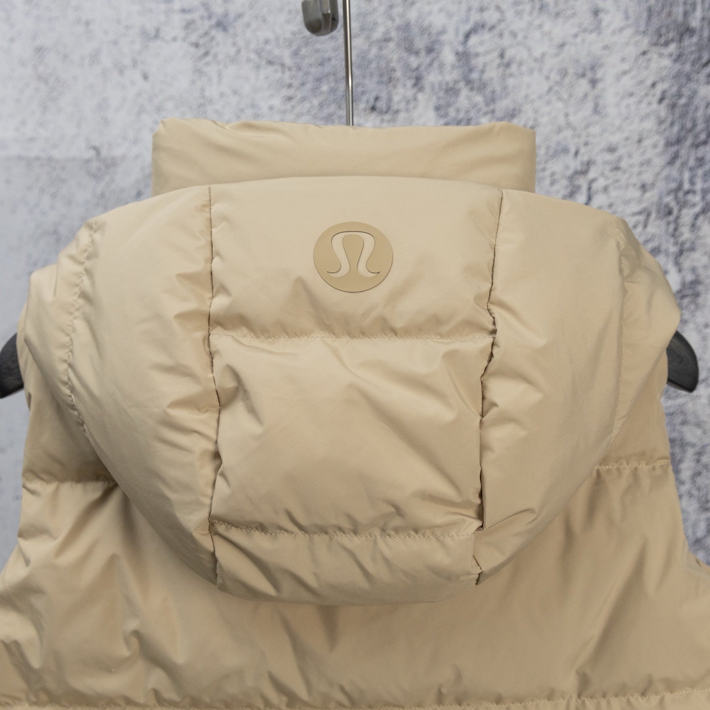 Tan hooded puffer jacket back view with embossed logo
