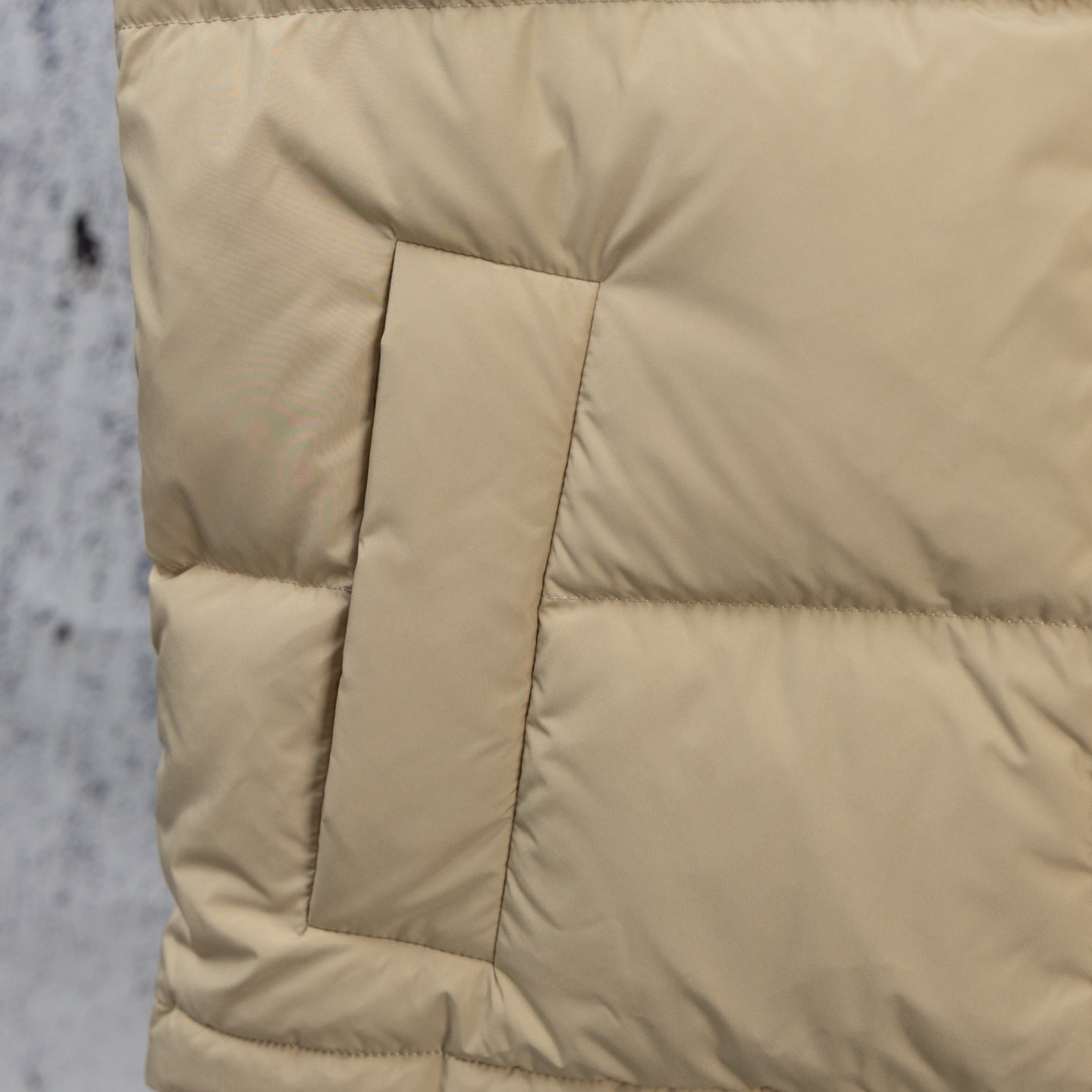 Beige puffer jacket quilting with vertical panel stitching and padded construction