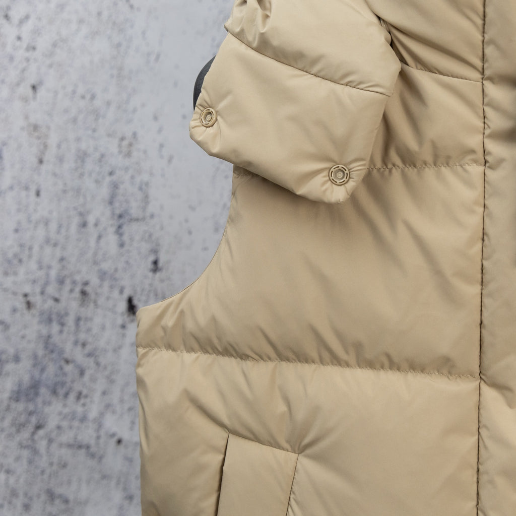 Beige puffer jacket side panel with quilted seams and snap shoulder strap