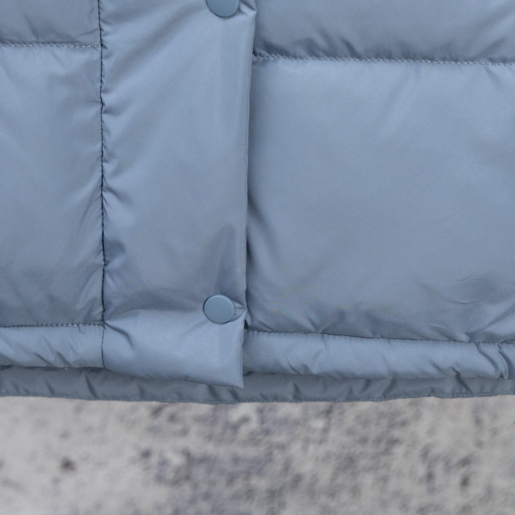 Light blue puffer vest front with two snap buttons and padded lower panel