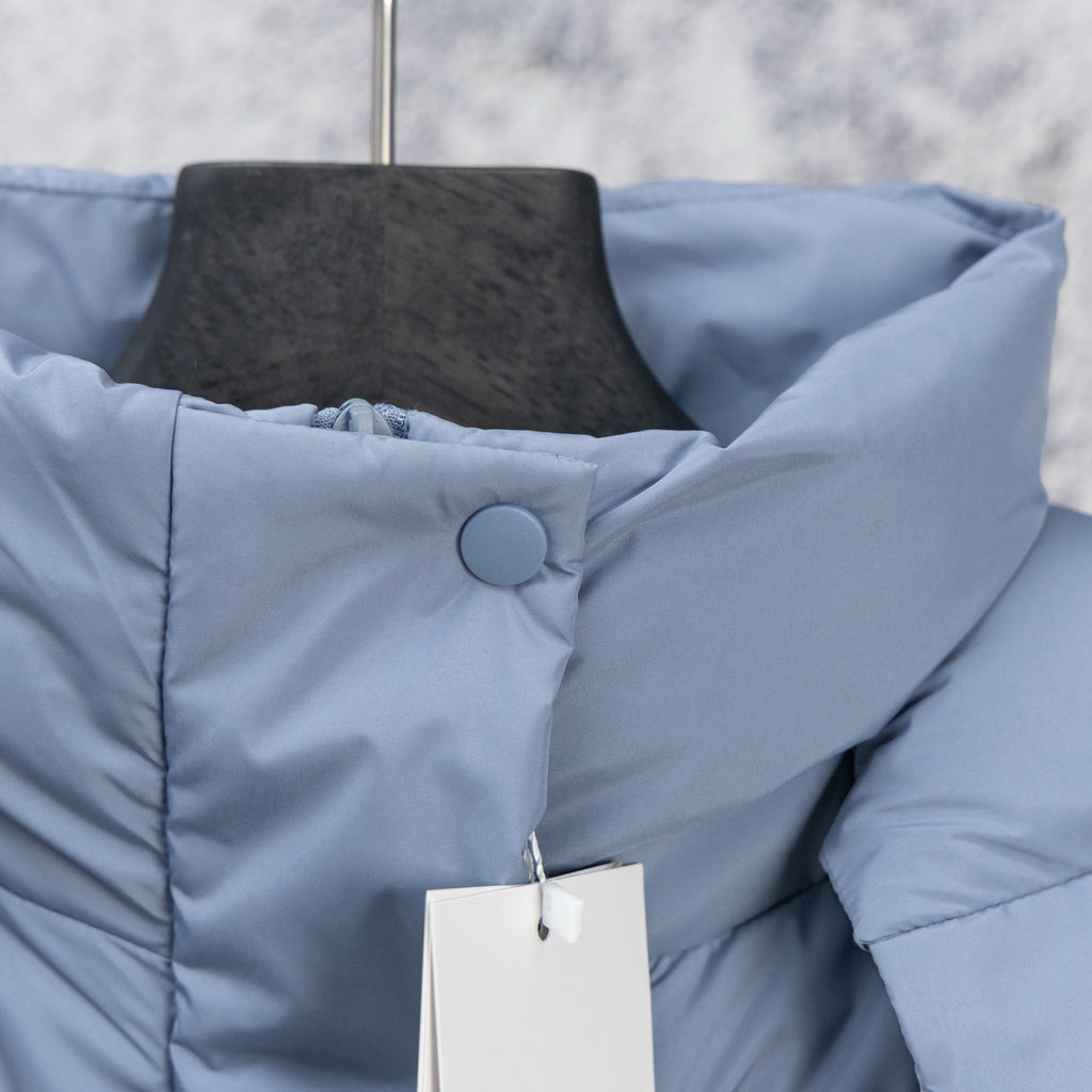 Light blue puffer vest close-up with stand collar and circular snap detail