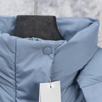 Light blue puffer vest close-up with stand collar and circular snap detail